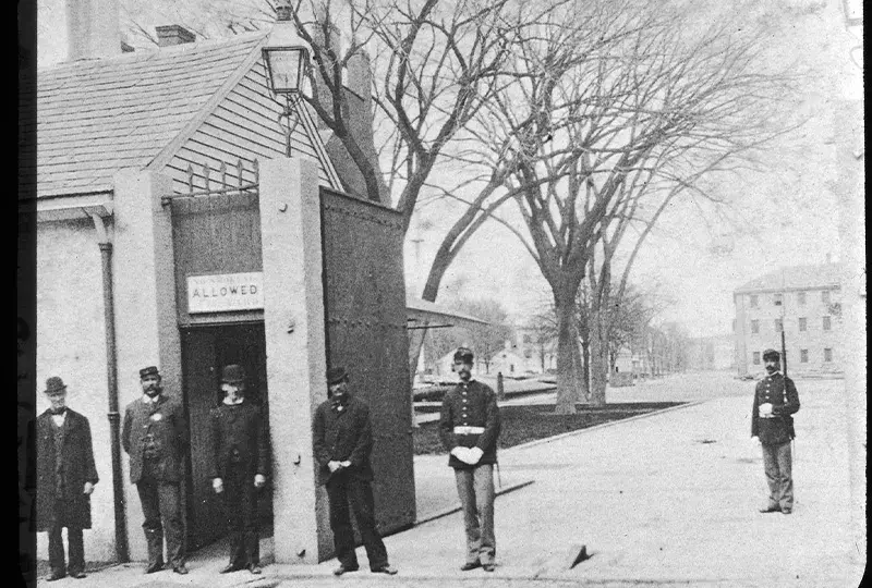 Old black and white photograph of 6 marines standing at a gate in the navy yard