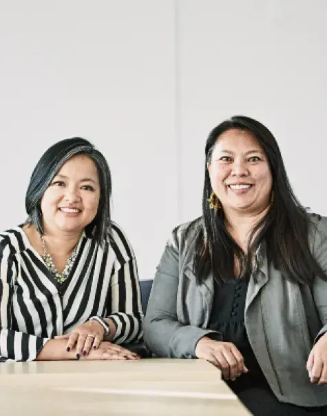 two Asian women sit at a table