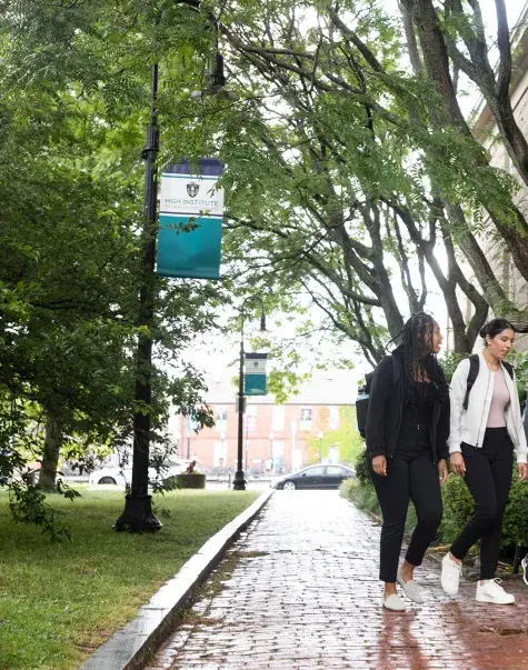 diverse women walking on a brick path through campus