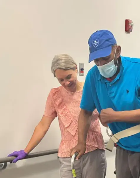 Man walks with cane and two physical therapists