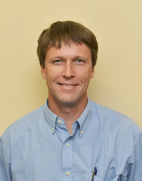 jason wears a blue collared shirt and a smile