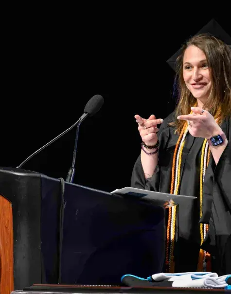 Woman in cap and gown talking at podium