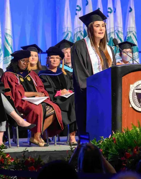 Woman in cap and gown talking at podium