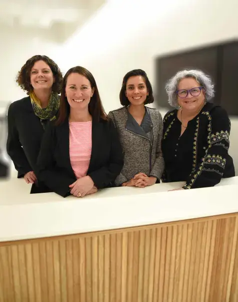 four women stand behind a desk