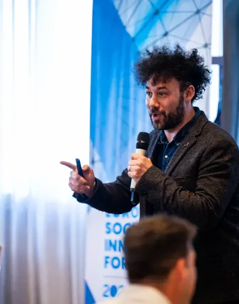 Man speaking to crowd with microphone 
