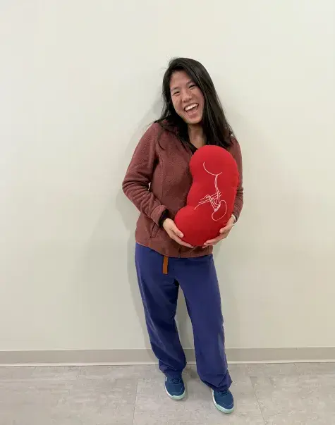 woman holds a kidney shaped pillow