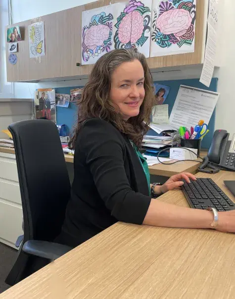 A woman sits at a desk with a keyboard in front of her