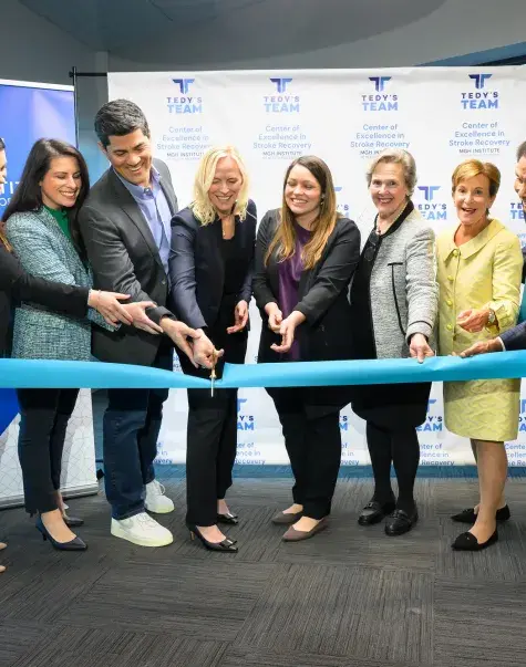 People cutting a ceremonial teal ribbon