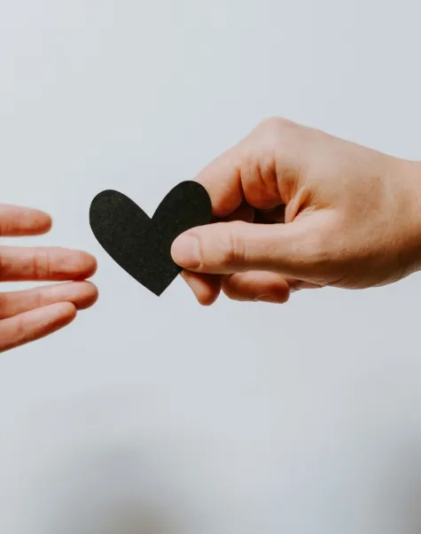 one hand handing a heart to another