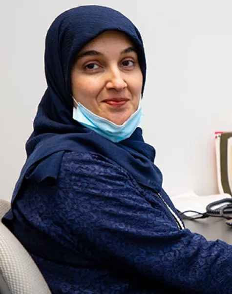 A woman sits at a desk with a laptop computer in front of her