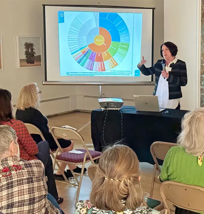 woman holding a microphone gestures in front of a crowd