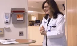 woman in a white lab coat enters a patient room in a hospital